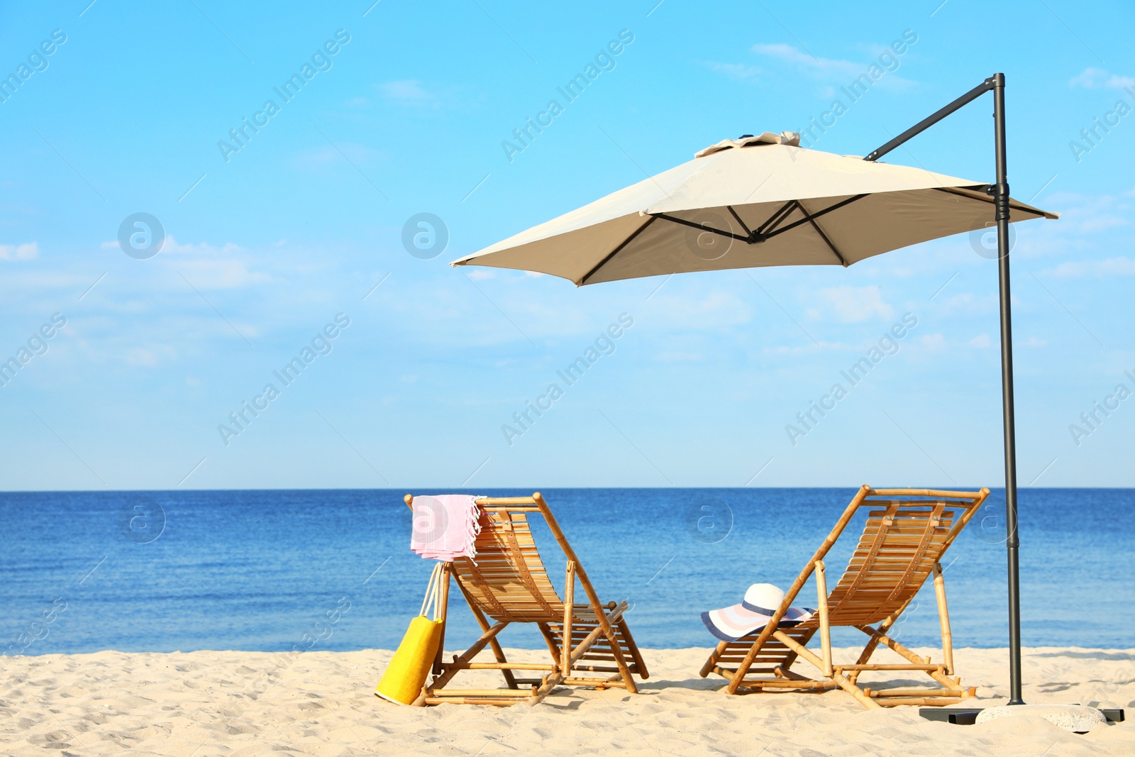 Photo of Empty wooden sunbeds and beach accessories on sandy shore