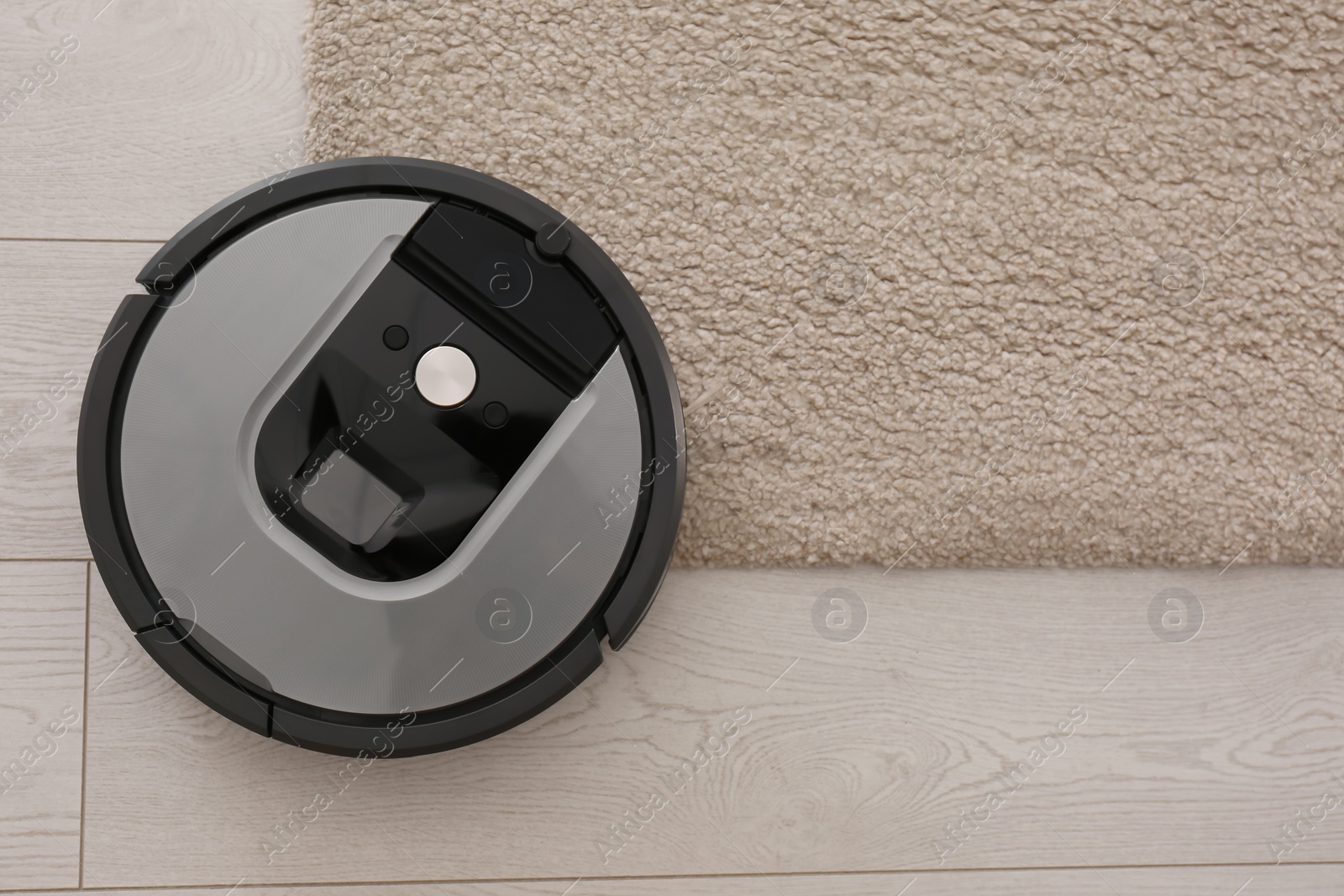 Photo of Modern robotic vacuum cleaner on beige carpet, top view. Space for text