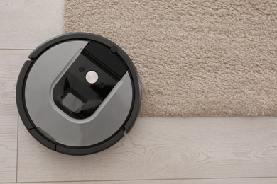 Modern robotic vacuum cleaner on beige carpet, top view. Space for text