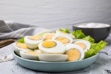 Fresh hard boiled eggs and lettuce on light grey textured table