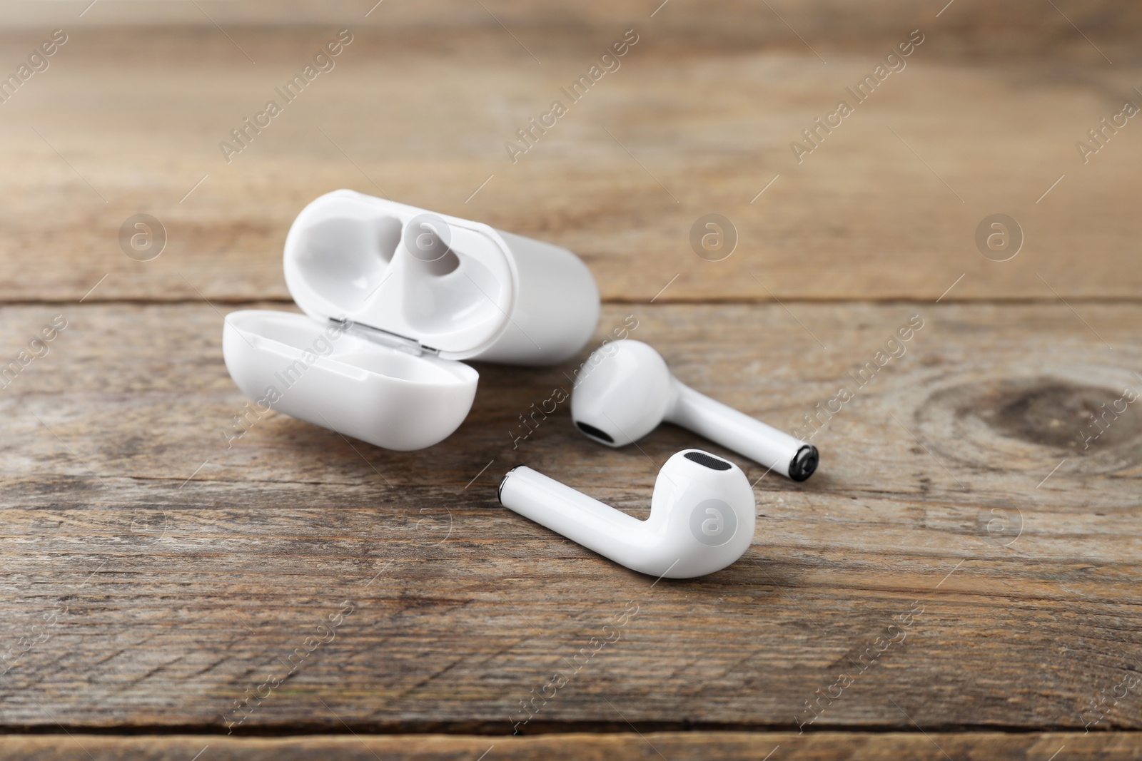 Photo of Wireless earphones and charging case on wooden table