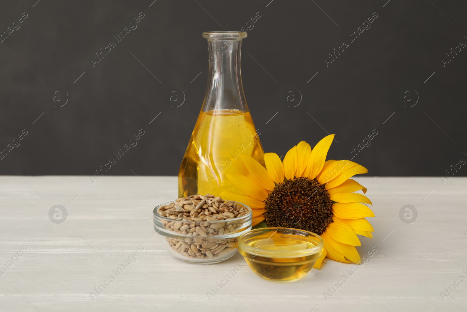 Photo of Sunflower, oil and seeds on white wooden table