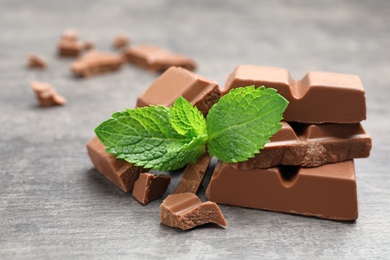 Pieces of milk chocolate with mint on gray table