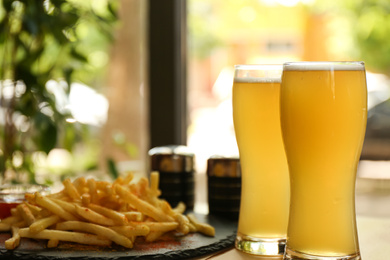 Photo of Delicious hot french fries and beer served on table