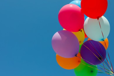Bunch of colorful balloons against blue sky, low angle view. Space for text