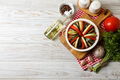 Cooking delicious ratatouille. Dish with different fresh cut vegetables on white wooden table, flat lay. Space for text