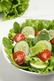 Photo of Delicious salad in bowl on white table, closeup