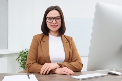 Photo of Happy young intern working at table in modern office