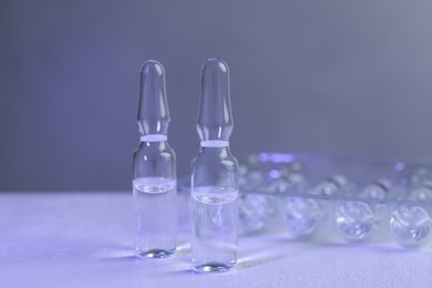 Photo of Pharmaceutical ampoules with medication on white table against grey background