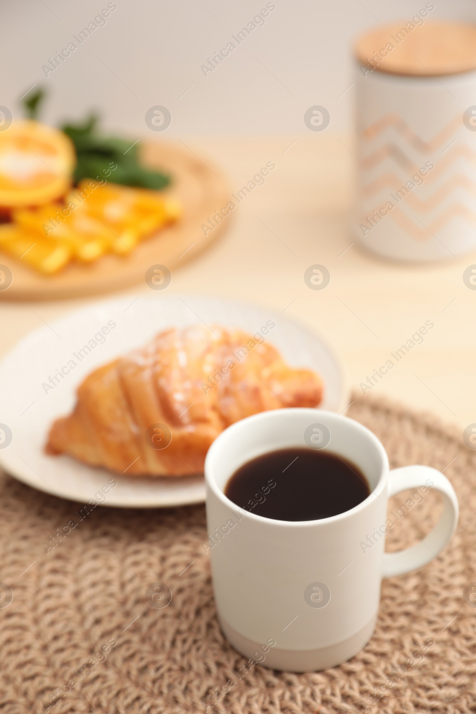 Photo of Cup of hot aromatic coffee and tasty croissant on table