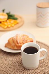 Photo of Cup of hot aromatic coffee and tasty croissant on table