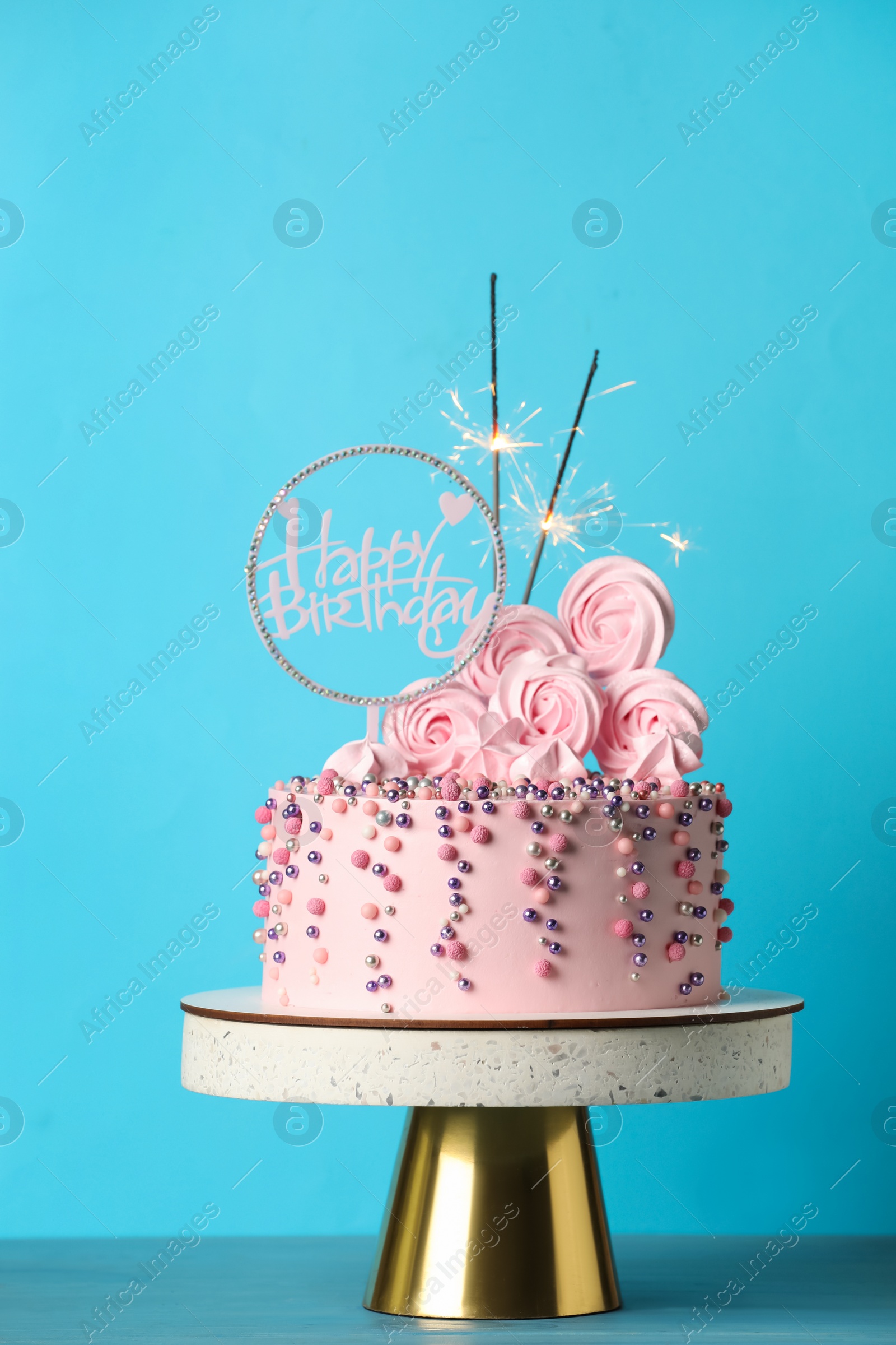 Photo of Beautifully decorated birthday cake with party decor on turquoise wooden table