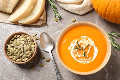 Delicious pumpkin soup in bowl on marble table, flat lay