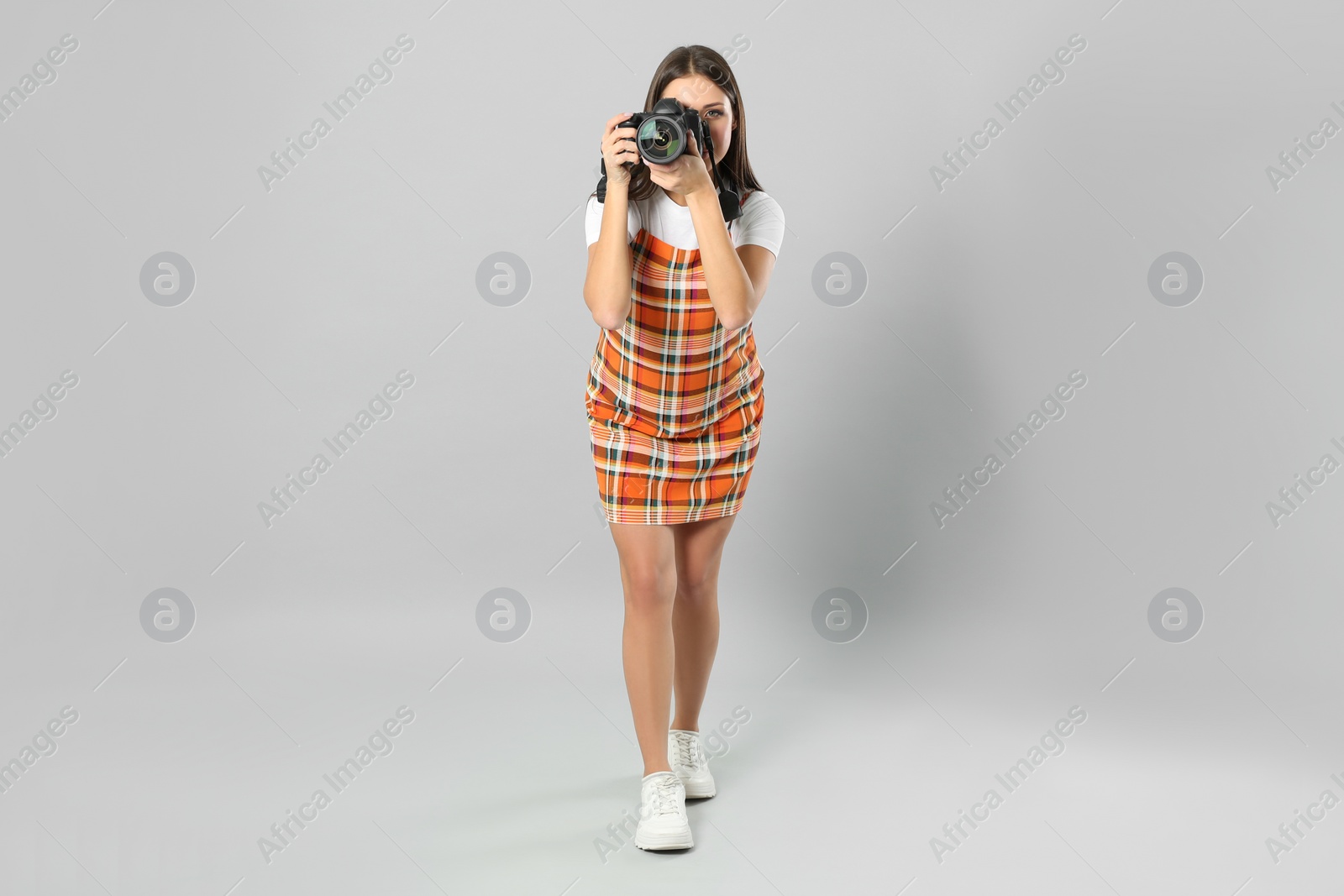 Photo of Professional photographer working on light grey background in studio