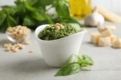 Bowl of tasty pesto sauce and ingredients on light table