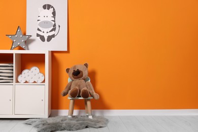 Photo of Beautiful children's room with bright orange wall and furniture, space for text. Interior design