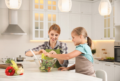 Mother and daughter cooking salad together in kitchen