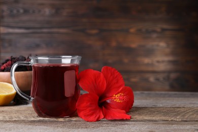 Photo of Delicious hibiscus tea and beautiful flower on wooden table. Space for text