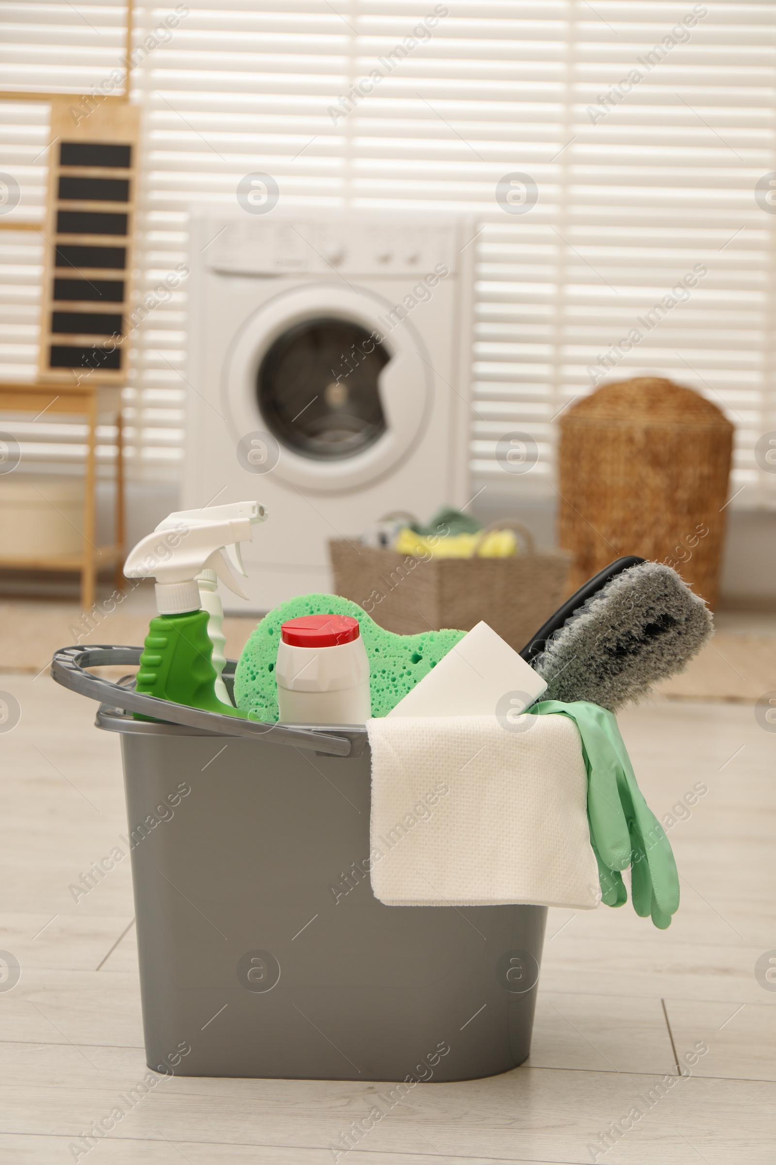 Photo of Different cleaning products in bucket on floor indoors