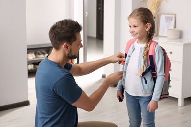 Photo of Happy father preparing his smiling daughter to school at home