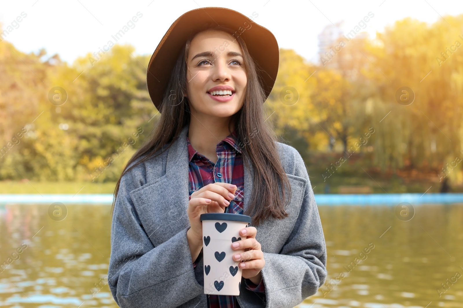 Photo of Portrait of young beautiful woman with drink in park. Autumn walk