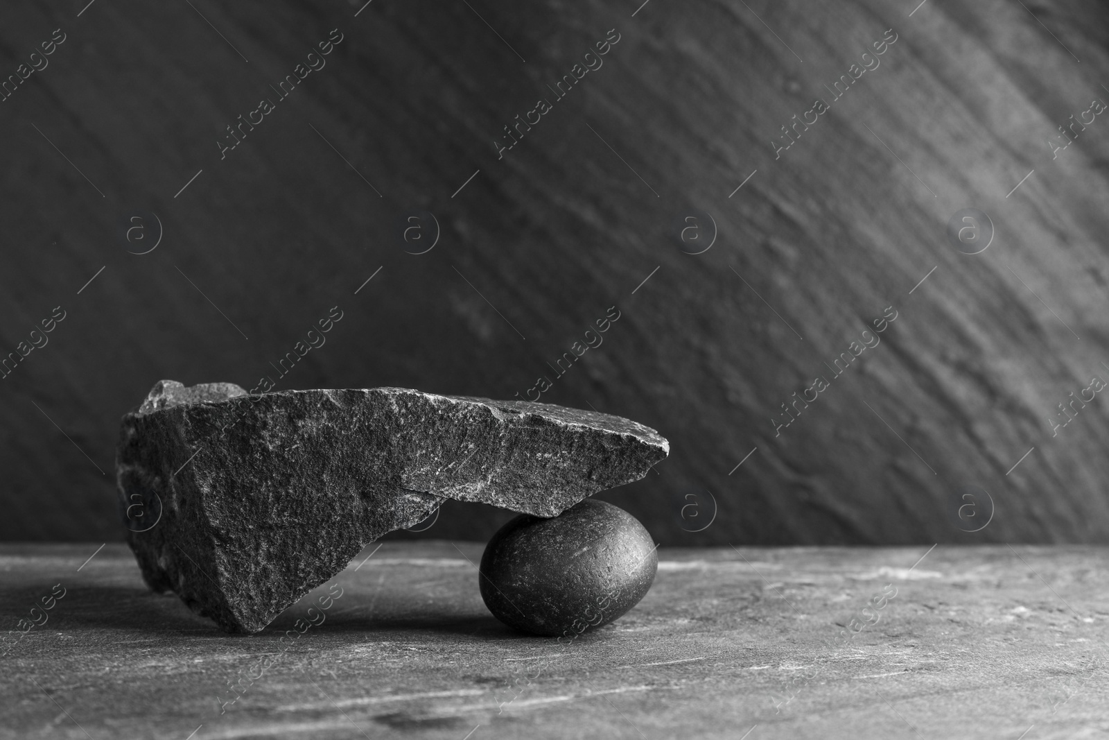 Photo of Presentation for product. Podium made of different stones on grey textured background. Space for text