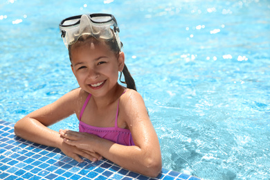 Photo of Little girl wearing diving mask in swimming pool. Summer vacation