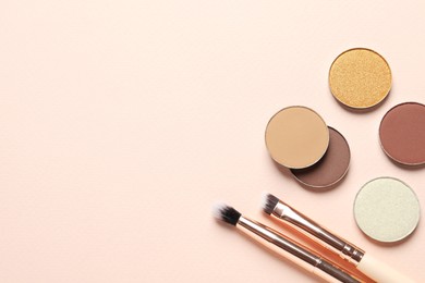 Photo of Different beautiful eye shadows and makeup brushes on beige background, flat lay. Space for text