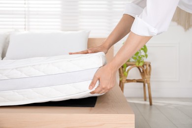 Photo of Woman putting soft white mattress on bed indoors, closeup