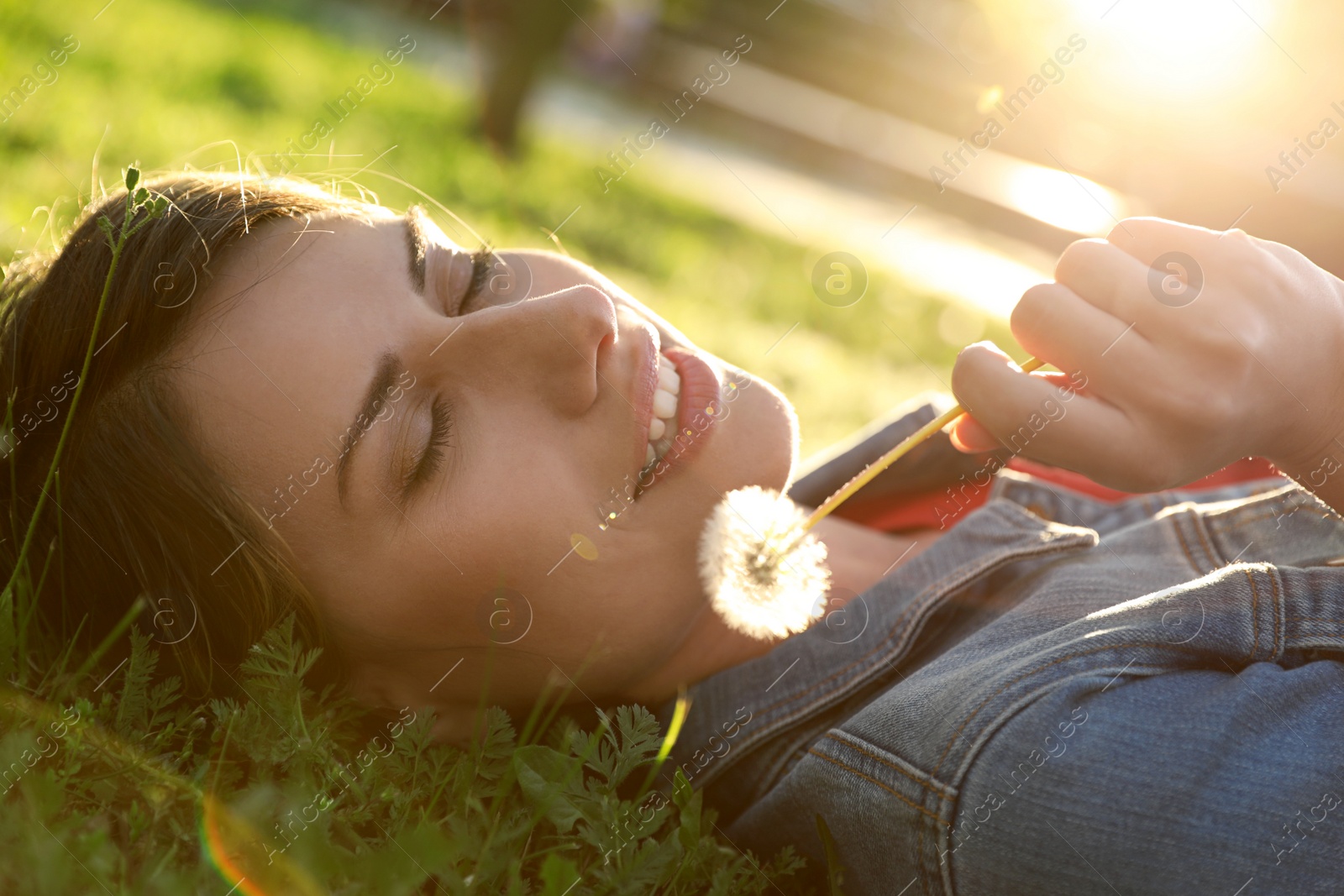 Photo of Young woman with dandelion in park on sunny day. Allergy free concept