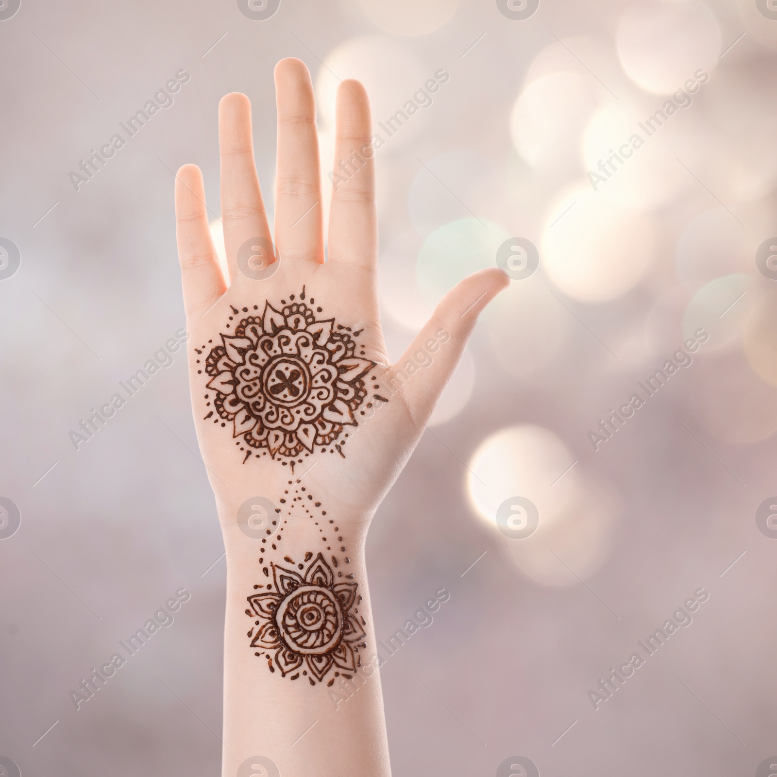 Image of Woman with henna tattoo on palm against blurred lights, bokeh effect