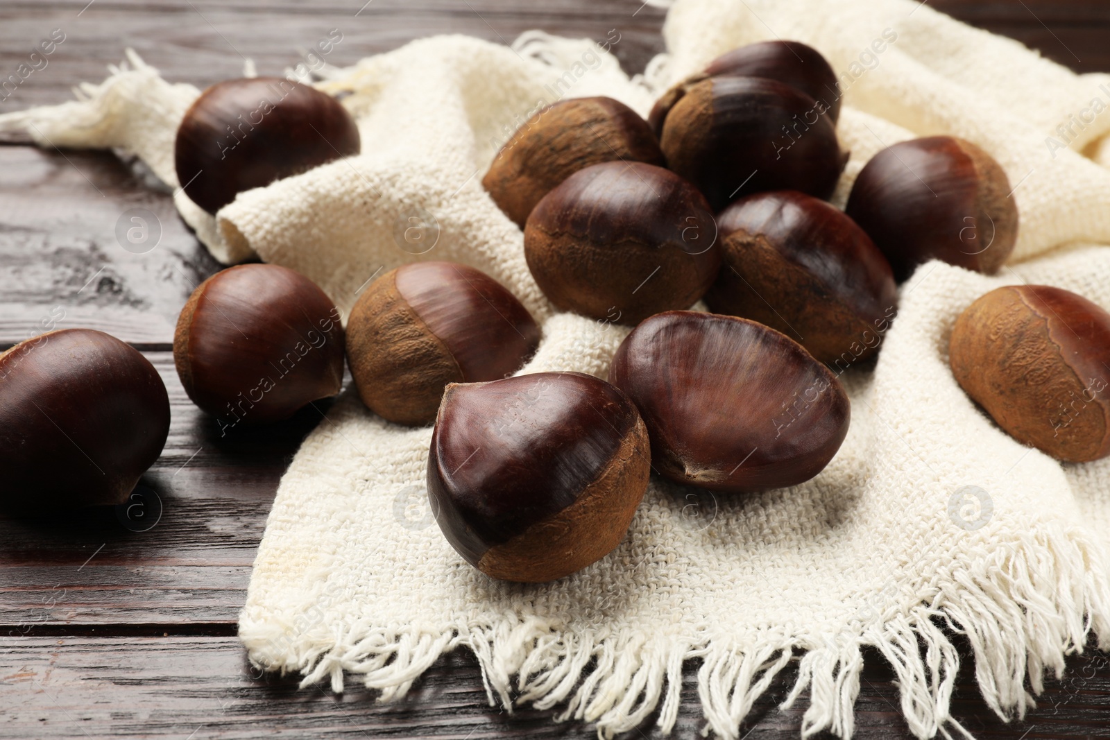 Photo of Sweet fresh edible chestnuts on wooden table, closeup