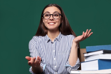 Portrait of young teacher at table against green background