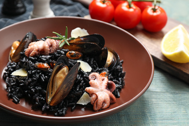 Photo of Delicious black risotto with seafood on blue wooden table, closeup