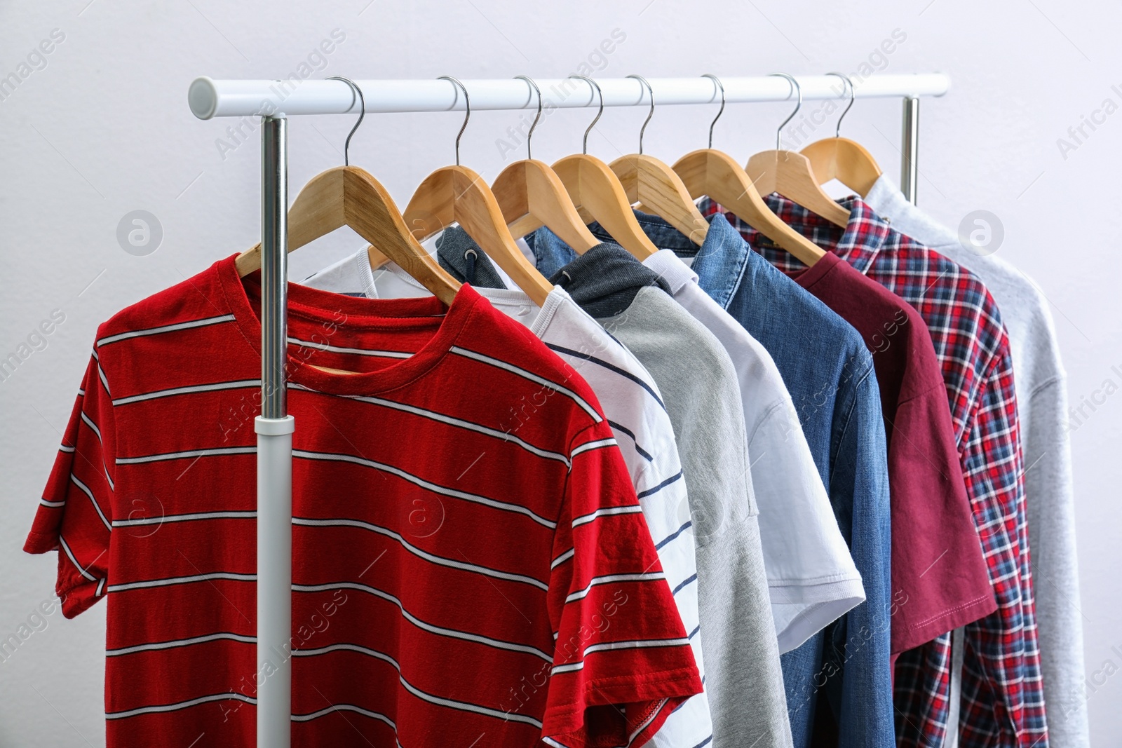 Photo of Stylish clothes hanging on wardrobe rack against light background