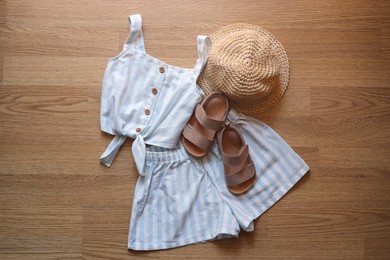 Photo of Stylish child clothes, shoes and hat on wooden background, flat lay