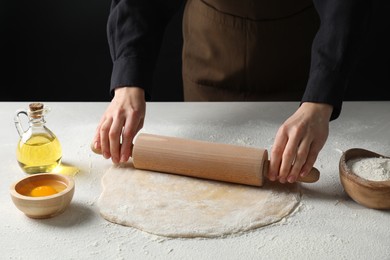 Photo of Woman rolling raw dough at table, closeup