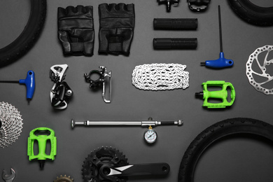 Photo of Set of different bicycle tools and parts on grey background, flat lay