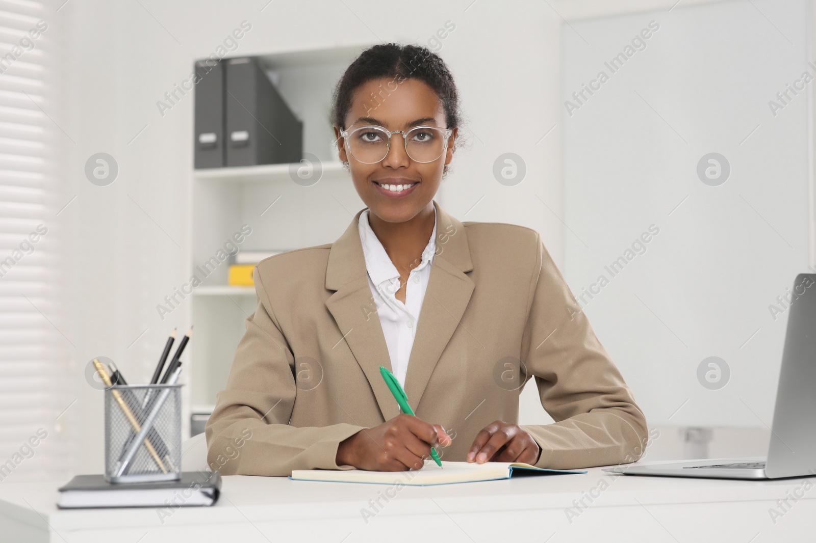 Photo of African American intern working at white table in office