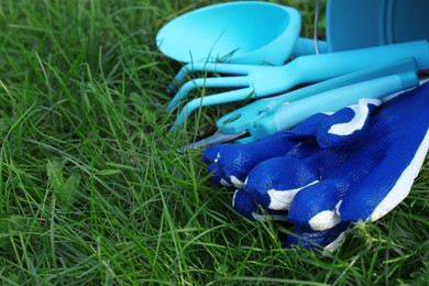 Bucket with gloves and gardening tools on grass outdoors, space for text