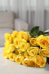 Beautiful bouquet of yellow roses on light grey table indoors, space for text