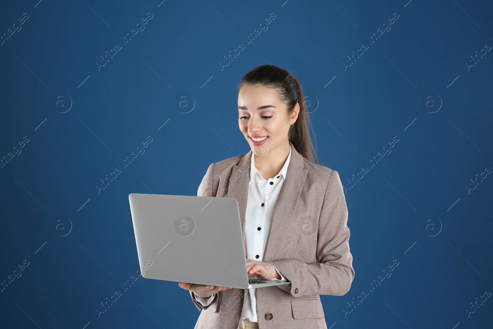 Photo of Portrait of young woman in office wear with laptop on color background