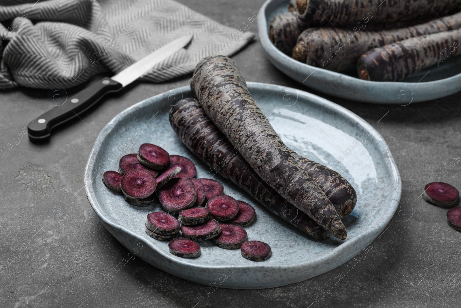 Photo of Fresh raw black carrots on grey plate