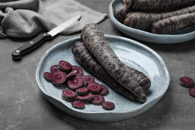 Fresh raw black carrots on grey plate