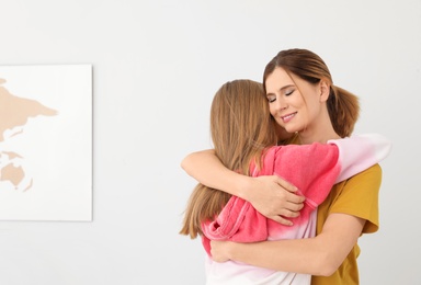 Happy mother hugging her teenager daughter at home