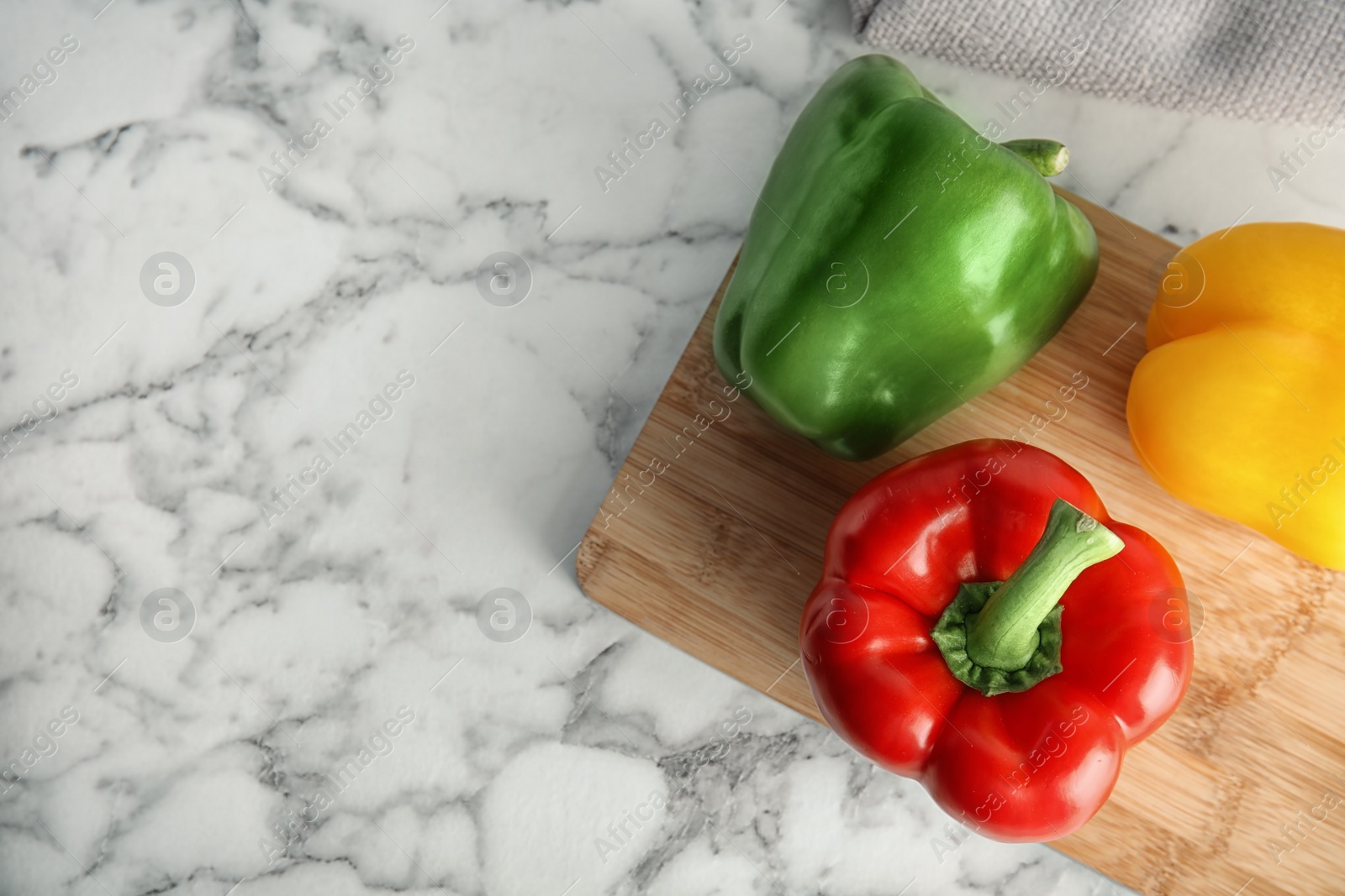 Photo of Wooden board with ripe paprika peppers on marble background, top view