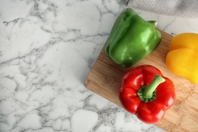 Wooden board with ripe paprika peppers on marble background, top view