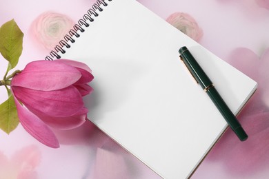 Guest list. Notebook, pen and magnolia on spring floral background, top view