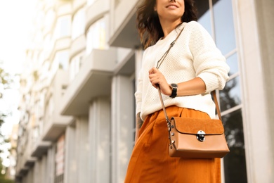 Photo of Young woman with stylish brown bag on city street, closeup