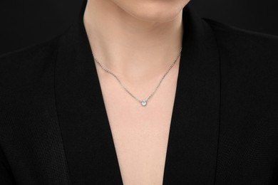 Woman with elegant necklace on black background, closeup